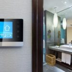 Smart thermostat in a clean bathroom with a sink and mirror, showcasing modern HVAC design by Charles Krull & Son, Inc.