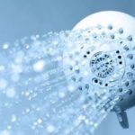 Modern showerhead with water spray in blue and white, showcasing plumbing maintenance tips from Charles Krull & Son, Inc.