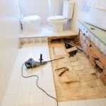 Bathroom renovation with plumbing tools and unfinished flooring, showcasing installation work by a plumbing contractor.