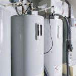 Two gray water heaters with pipes in a plumbing setting by Charles Krull & Son, Inc.