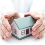 Hands protectively hold a small, stylized house, illustrating the importance of plumbing maintenance for homeowners.