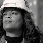 Woman in hard hat at construction site, showcasing strength as a notable plumbing figure for Charles Krull & Son, Inc.