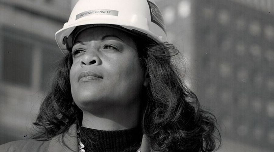Adrienne Bennett, a pioneering Black woman in plumbing, wearing a hard hat and looking confidently into the distance, symbolizing empowerment and breaking barriers in the trades.