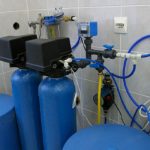 Blue cylindrical tanks and control panel in a water filtration system by Charles Krull & Son, Inc. plumbing services.