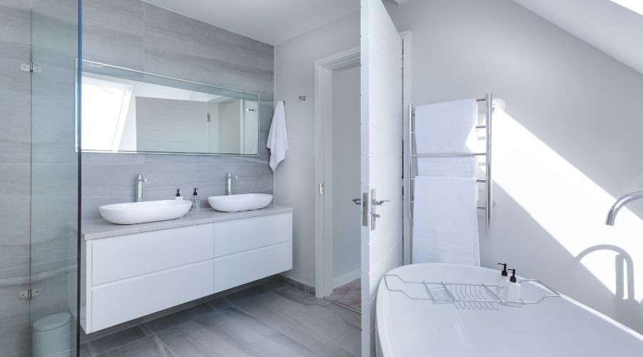 Modern bathroom featuring a double sink vanity, freestanding bathtub, and wall-mounted mirrors by a plumbing service.