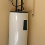 Water heater with a white cylindrical body and tubing for plumbing services by Charles Krull & Son, Inc.